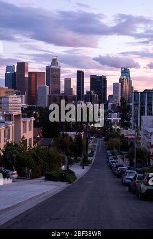 Skyline von Los Angeles bei Sonnenuntergang mit bunten rosa und goldenen Wolken am Himmel, wie aus Angelino Heights Nachbarschaft betrachtet Stockfoto