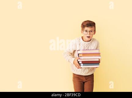 Überrascht kleinen Jungen mit Büchern auf farbigen Hintergrund Stockfoto