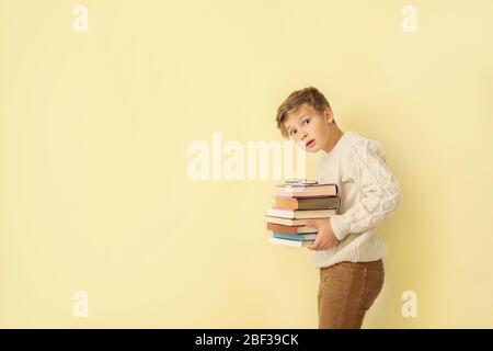 Überrascht kleinen Jungen mit Büchern auf farbigen Hintergrund Stockfoto