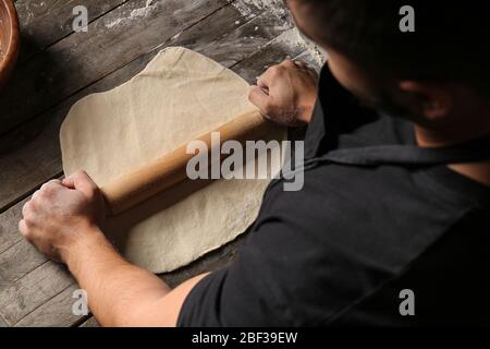 Mann rollt Teig in der Küche aus Stockfoto