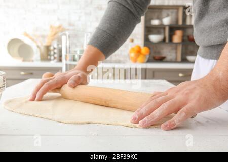 Mann rollt Teig in der Küche aus, Nahaufnahme Stockfoto