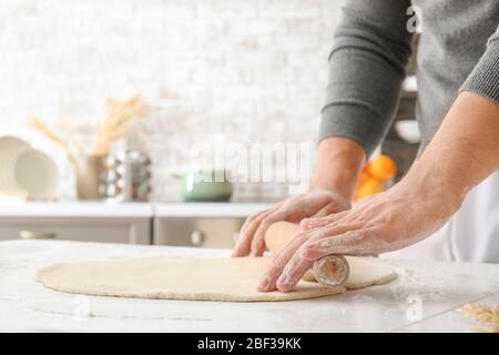 Mann rollt Teig in der Küche aus Stockfoto