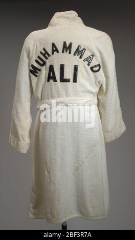 Weiße Frottee-Robe, die Muhammad Ali während des Trainings am Deer Lake getragen hat. Diese weiße Frottee-Robe (a) und der Gürtel (b) wurden von Muhammad Ali während des Trainings im Jahr 1980 am Deer Lake, Pennsylvania, für einen Kampf gegen Larry Holmes verwendet. Die Robe hat lange Ärmel, einen gedrehten Kragen und fällt knapp unter die Knie. Stockfoto