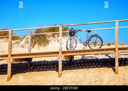 Fahren Sie mit dem Fahrrad auf einer Strandpromenade über dem Sand Stockfoto