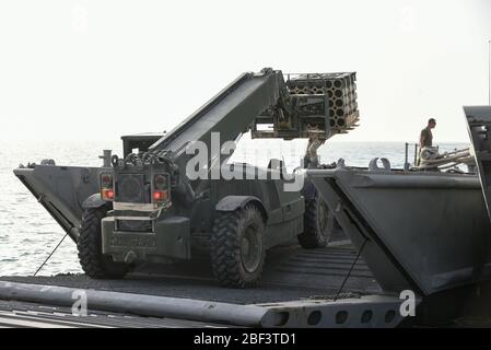 US Army Soldiers from 1098TC and 331st Transportation Company, 11th Trans. Bataillon, 7. Trans. Brigade (Expeditionary), Betrieb eines US Navy Landing Craft Mechanized (LCM) und Gabelstapler zum Herunterladen US Marine Artillerie Munition während Joint Logistics-over-the-Shore Übung Native Fury 20 in den Vereinigten Arabischen Emiraten, 09. März 20Native Fury 20 ist eine gemeinsame Übung mit Live-Feuer und Manöver Ausbildung mit städtischen Umwelt Trainingseinrichtungen, Entwicklung von Fähigkeiten und Austausch mit den Streitkräften der Vereinigten Arabischen Emirate, Schiff-an-Land-Abladungen von Personal, Ausrüstung und Humanita Stockfoto