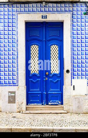 Kunstvolle klassische blaue Tür in einem Gebäude mit geometrischen blauen Azulejo-Fliesen Stockfoto