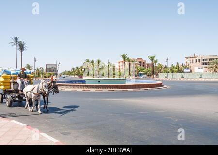 Marrakesch, Marokko - 8. September 2010: Mann auf Pferd und Wagen, der Waren um einen Kreisverkehr herum trägt. Diese Art des Transports wird noch genutzt. Stockfoto