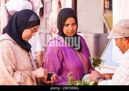 Marrakesch, Marokko - 8. September 2010: Frauen kaufen Kräuter von einem Händler. Straßenmärkte werden jeden Tag / Stockfoto