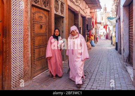 Marrakesch, Marokko - 8. September 2010: Frauen gehen eine typische Straße entlang. Lange Bademäntel sind normal Stockfoto