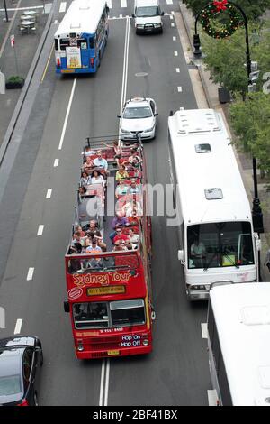 Blick über den Verkehr und einen offenen Doppeldeckerbus mit Touristen, die durch das CBD von Sydney fahren. New South Wales, Australien. Stockfoto