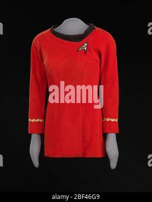 Rote Sternenflottenuniform, getragen von Nichelle Nichols als LT Uhura auf Star Trek. Diese rote Sternenflottenuniform wurde von Nichelle Nichols als die Figur LT. Uhura in der Fernsehserie Star Trek getragen. Das rote Minikleid ist aus synthetischem Velours-Stoff mit goldfarbenen Zöpfen und einem schwarzen Strickkragen gefertigt. Stockfoto