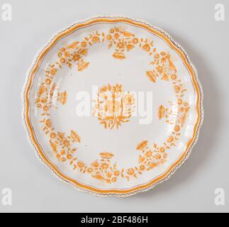 Platte. Kreisförmige Form mit geformtem Rand. Monochrome ockerfarbene Dekoration zeigt Kartoffelblüten in der Mitte und um den Rand. Stockfoto