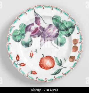 Obst- oder Dessertplatte. Flacher Marlmary, der von einem gebeulten inneren Rand gesprenkelt wird. Hochgezogene, gefiederte Kante, braun und grün lackiert. In der Mitte, große und kleine Gurke und ein Apfel. Auf Marlilie, drei Hagebutten, ein lila langer Radieschen, Strömungen und kleine rote Beeren. Stockfoto