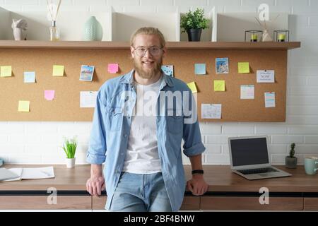 Lächelnd zuversichtlich tausendjährigen Geschäftsmann Blick auf Kamera im Home Office. Stockfoto