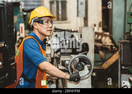 Asian Woker ist stolz auf seine Arbeit in der Schwerindustrie im Produktionslinienprozess und lächelt in der Fabrik glücklich. Stockfoto