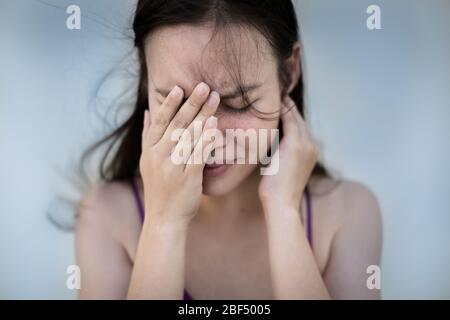 Eine Frau, die ihr Gesicht frustriert und emotional Blautöne hält. Stockfoto