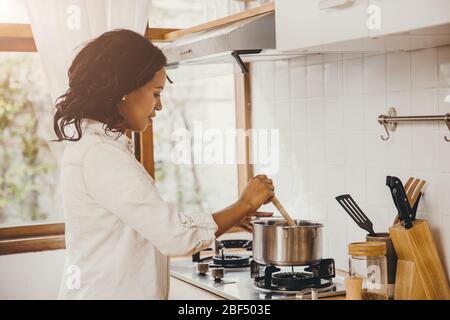 African American Black Frau Kochen kochende Suppe in der Küche zu Hause. Stockfoto