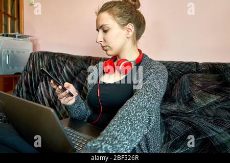 Frau mit Laptop, die ihr Telefon überprüft. Home Office. Stockfoto