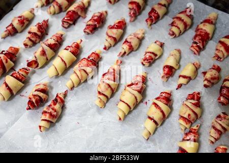 Großmutter, die vor dem Backen in der Küche im Innenbereich handgemachte leckere Butter mit Obst- und Beerenmarmelade auf dem Backblech zubereitet. Rolled Spin hausgemacht Stockfoto