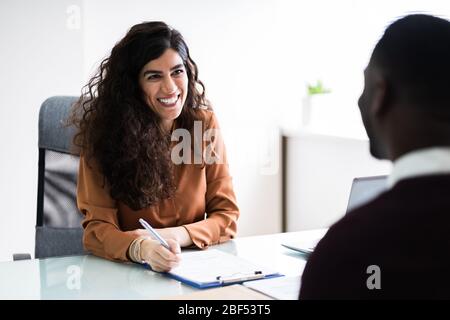 Weibliche Führungskraft interviewing EINEN jungen männlichen Bewerber im Büro Stockfoto