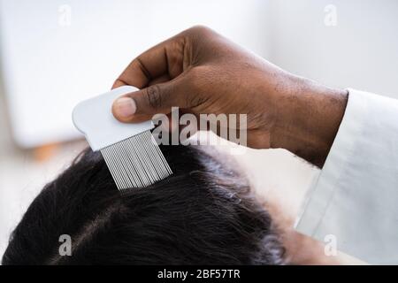 Nahaufnahme der Person Hand mit Läusen Kamm auf der Patientin Haar Stockfoto