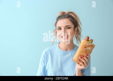 Porträt von schönen jungen Frau mit Französisch Hot Dog auf farbigen Hintergrund Stockfoto