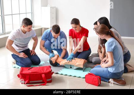 Instruktoren, die die HLW an Schaufensterpuppen im erste-Hilfe-Kurs demonstrieren Stockfoto