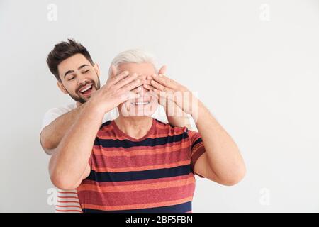 Junger Mann und sein Vater haben Spaß auf leichtem Hintergrund Stockfoto