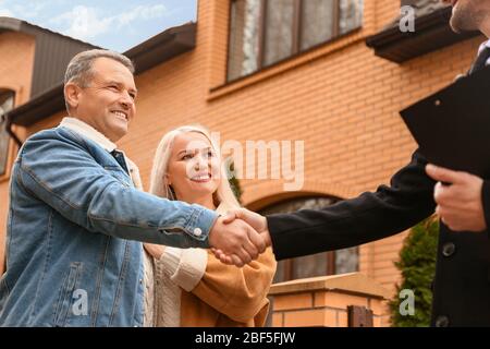 Männlich Immobilienmakler Händeschütteln mit reifen paar in der Nähe Haus im Freien Stockfoto
