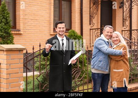 Männlich Immobilienmakler mit Schlüssel und reifes Paar in der Nähe Haus zum Verkauf im Freien Stockfoto