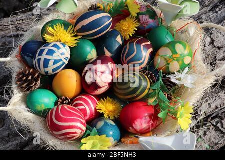 Ostereierkorb mit bunt bemalten Eiern mit Blumen auf Walnussrinde Hintergrund verziert Stockfoto
