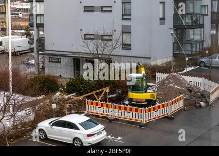 Die geothermische Wärme ist eine moderne Option, um Häuser in Finnland aufzuwärmen. Kleiner Bagger graben Boden für benötigte unterirdische Arbeiten. Stockfoto