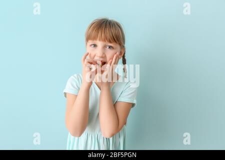 Kleines Mädchen, das Fischölpille vor Farbhintergrund nimmt Stockfoto