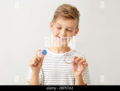 Kleiner Junge mit Kontaktlinsenhülle und Brille auf grauem Hintergrund Stockfoto