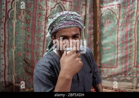 Beduinen in traditioneller Kleidung trinken Tee auf einem Teppich in der saudischen Wüste, Saudi-Arabien Stockfoto