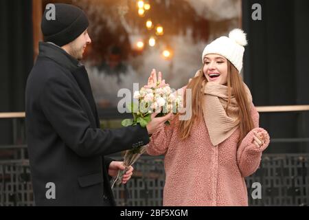 Schöne junge Frau, die am romantischen Tag im Freien Blumen von ihrem Freund erhält Stockfoto