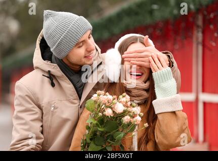 Schöne junge Frau, die am romantischen Tag im Freien Blumen von ihrem Freund erhält Stockfoto