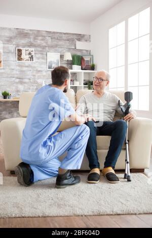 Alter Mann mit geistiger Gesundheit erkennen seinen Arzt im Pflegeheim. Hausmeister im Gespräch mit dem alten Mann. Stockfoto