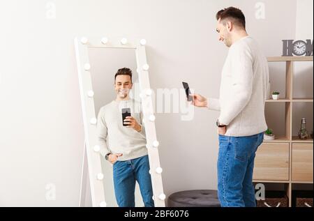 Schöner junger Mann, der zu Hause Selfie vor dem Spiegel nimmt Stockfoto