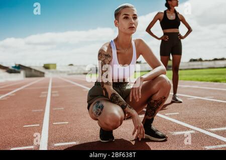 Sportlerinnen auf der Laufstrecke vor dem Rennen. Junge Läuferinnen bereiten sich auf das Rennen im Stadion vor. Stockfoto