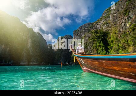 Schöner Mann Tourist, sitzt auf einem Boot mit blauem türkisfarbenem Meerwasser, Phi phi Insel mit blauer Lagune in der Sommersaison während der Reise Vacatio Stockfoto