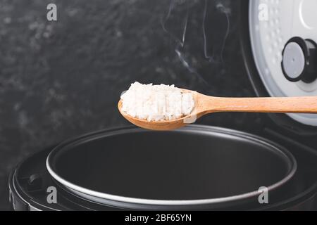 Löffel mit gekochtem Reis auf dunklem Hintergrund Stockfoto