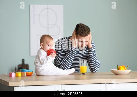 Junger Mann, der an postnataler Depression in der Küche leidet Stockfoto