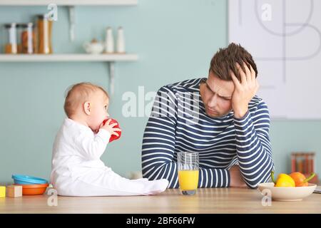 Junger Mann, der an postnataler Depression in der Küche leidet Stockfoto