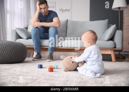 Junger Mann, der zu Hause an postnataler Depression leidet Stockfoto