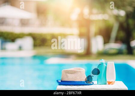 Sonnencreme-Flaschen, Brillen, Seesterne am Rand des Pools Stockfoto