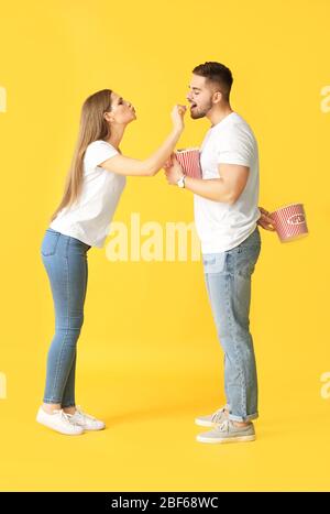 Emotional junges Paar mit Popcorn auf Farbhintergrund Stockfoto