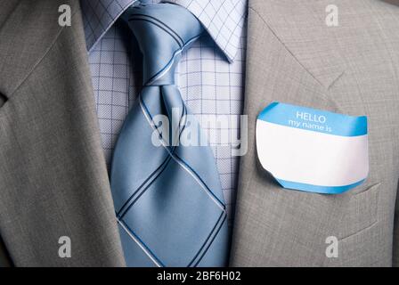 Nahaufnahme eines leeren Namensschildes, das vom Revers des Anzugs eines nicht erkennbaren Geschäftsmannes abblättert Stockfoto