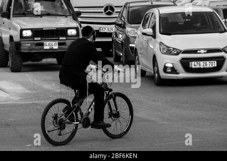 Jerusalem, Israel. April 2020. Ein ultra-orthodoxer jüdischer junger Mann fährt mit dem Fahrrad vor dem Verkehr, während Polizeisperren die vollständige Schließung religiöser Viertel in Jerusalem mit vermehrten Coronavirus-Infektionen erzwingen. Die Zahl der bestätigten COVID-19-Fälle in Israel steigt auf 12,855 mit 148 Todesfällen. Quelle: Nir Alon/Alamy Live News Stockfoto