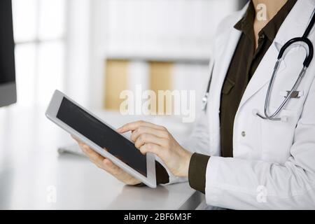 Unbekannter weiblicher Arzt mit Tablet-Computer in der Klinik. Perfekter medizinischer Service im Krankenhaus. Medizinkonzept Stockfoto